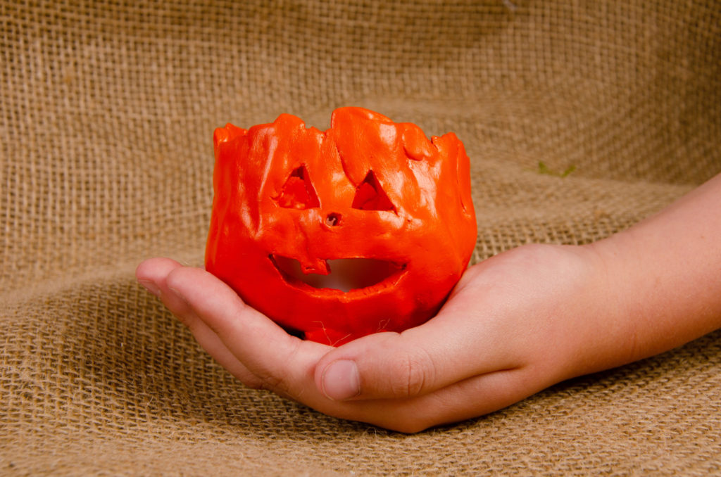 Child holding a small clay pumpkin lantern