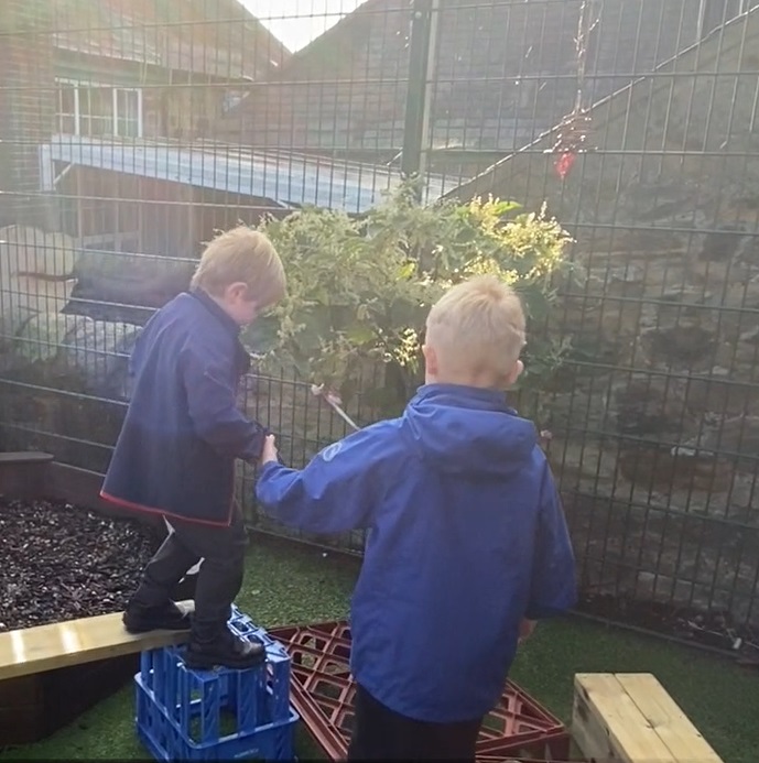 Year one pupil helps a reception pupil on the balance trail.