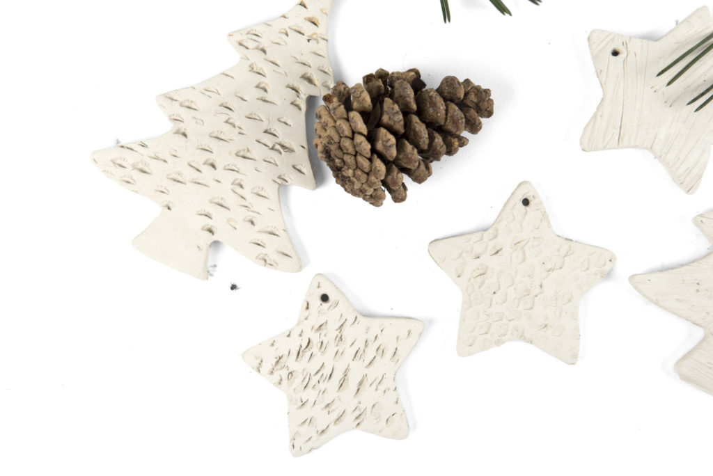 Pressing pine cones into clay