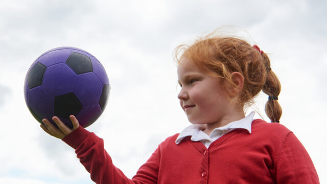 Girl holding up football in hand