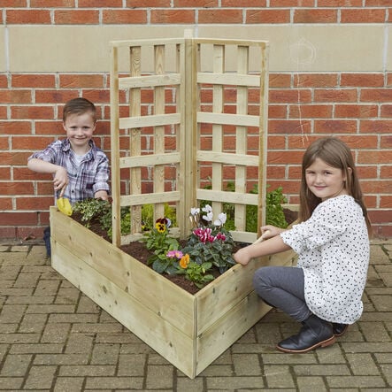 Image shows an outdoor planter with trellis, featuring two school children planting flowers in the planter. 