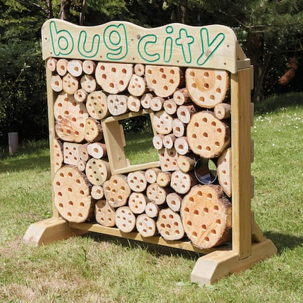 Photograph shows a Giant outdoor bug hotel sitting on grass.