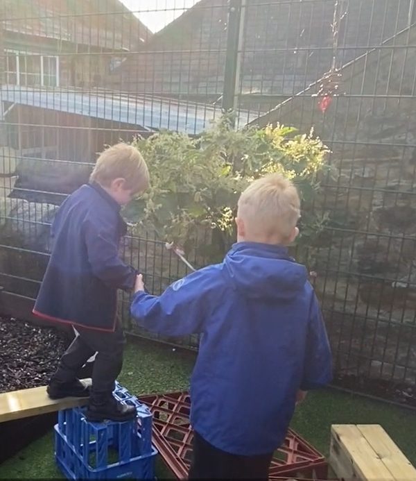 Year one pupil helps a reception pupil on the balance trail.