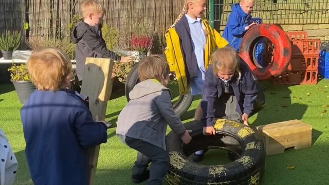 Children work together to lift and move tires and planks.