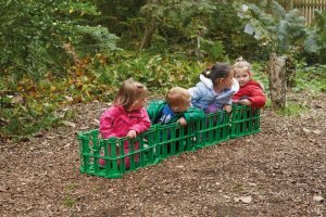 Loose parts play - children sitting in crates used to symbolise a train or a carriage 