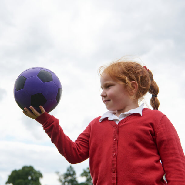 Girl holding up football in hand