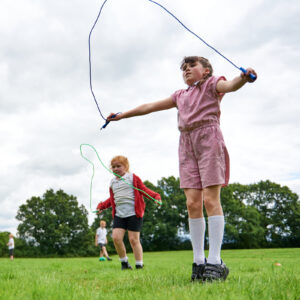 Two girls skipping on field