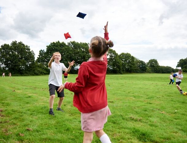 Boy and girl in a field throwing bean bags to one another