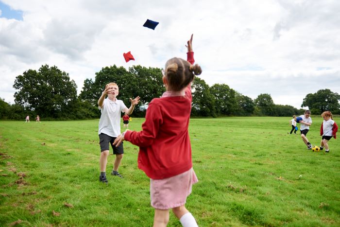 Boy and girl in a field throwing bean bags to one another