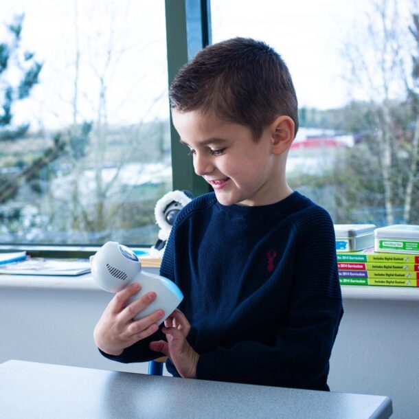 School boy holding a Kitt robot and looking down smiling at him.