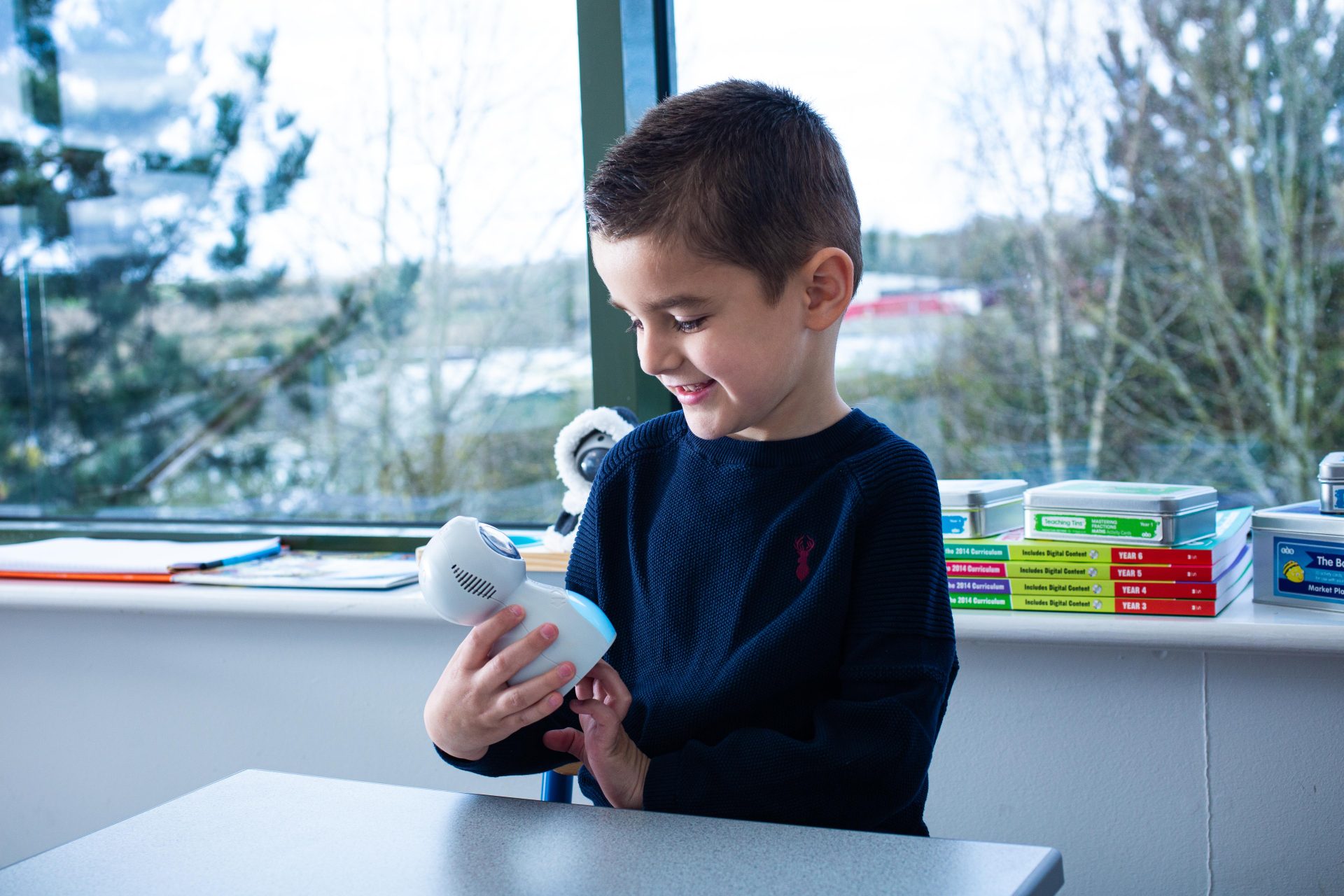 School boy holding a Kitt robot and looking down smiling at him.