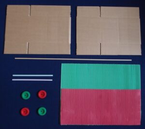 Image shows two flattened cardboard boxes, coloured corrugated card, wheels, straws and dowel.
