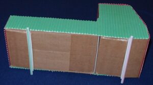 Cardboard cabin turned on its side to show two straws underneath.