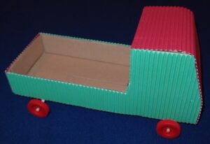 Red and green cardboard cabin with wheels attached