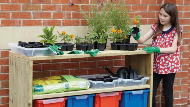 Image shows a Small Outdoor Mobile Storage Shelving Unit, containing plants on top and gardening tools underneath. A child is tending to one of the plants on the top.