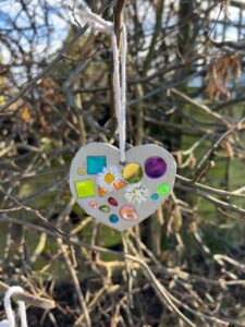 A handmade Mother's Day clay suncatcher hanging in a tree