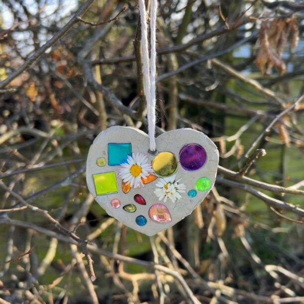 A handmade Mother's Day clay suncatcher hanging in a tree