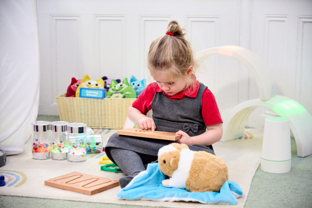 Child using a breathing board and weighted lap buddy in an inclusive classroom space.