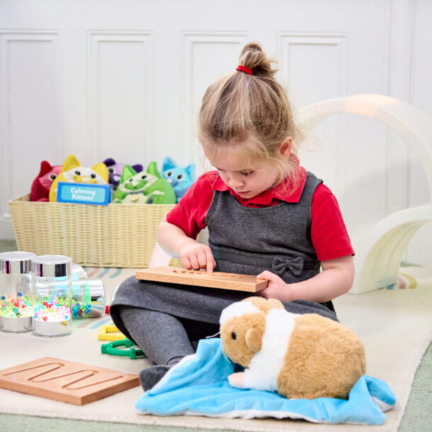Child using a breathing board and weighted lap buddy in an inclusive classroom space.